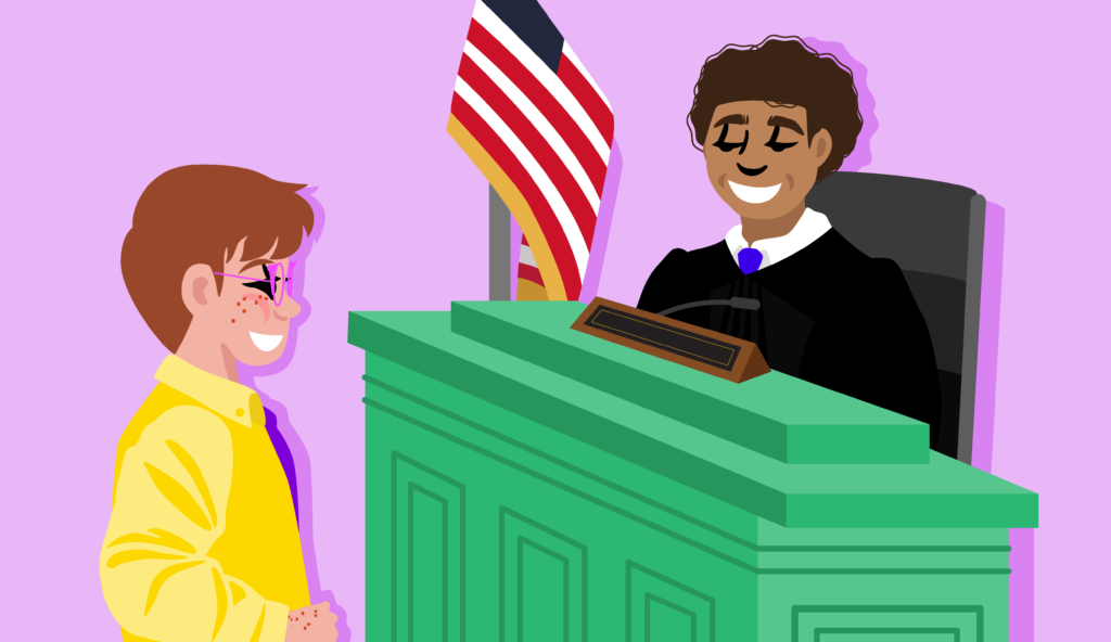 Picture of a male-presenting youth in a button-down shirt standing in front of a male-presenting judge sitting at their bench with an American flag on a flag pole in the background.